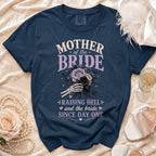 Navy blue t-shirt with "Mother of the Bride Raising Hell and the Bride Since Day One" text and skeleton hand holding roses.