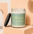 Glass candle with "Officiated by a friend" text on a light green label.