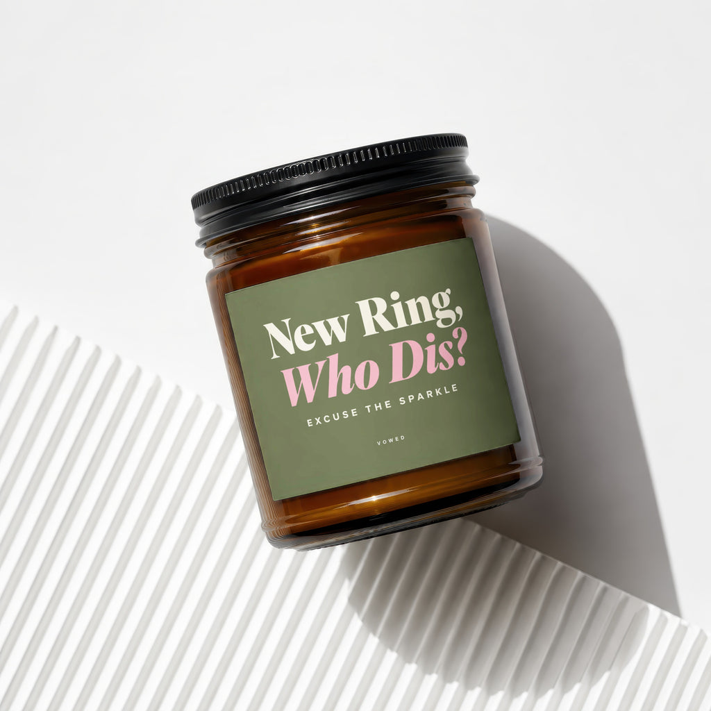 Amber candle in glass jar with a green label reading "New Ring, Who Dis?"