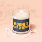 Glass jar candle with "Appointed: Moonlit Maid of Honor" text, surrounded by pink petals.
