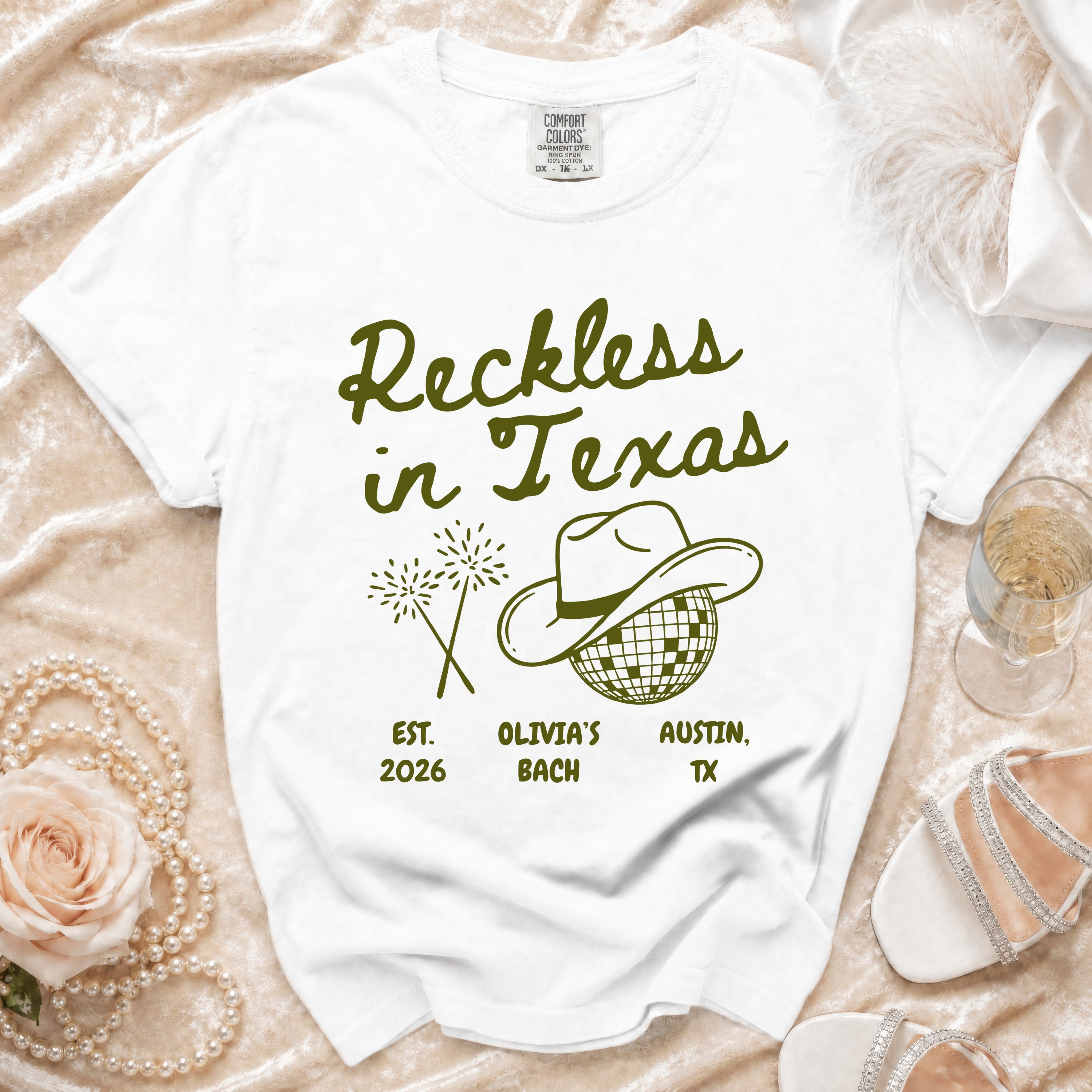 White t-shirt with "Reckless in Texas" text, cowboy hat, and fireworks.