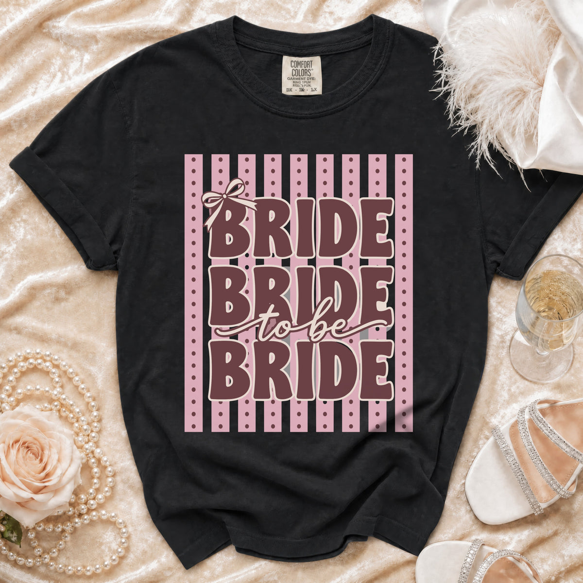 Black t-shirt with "Bride to Be Bride" text and a bow on pink stripes.