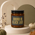 Brown glass candle labeled "Bound in Black Lace" with floral accents.