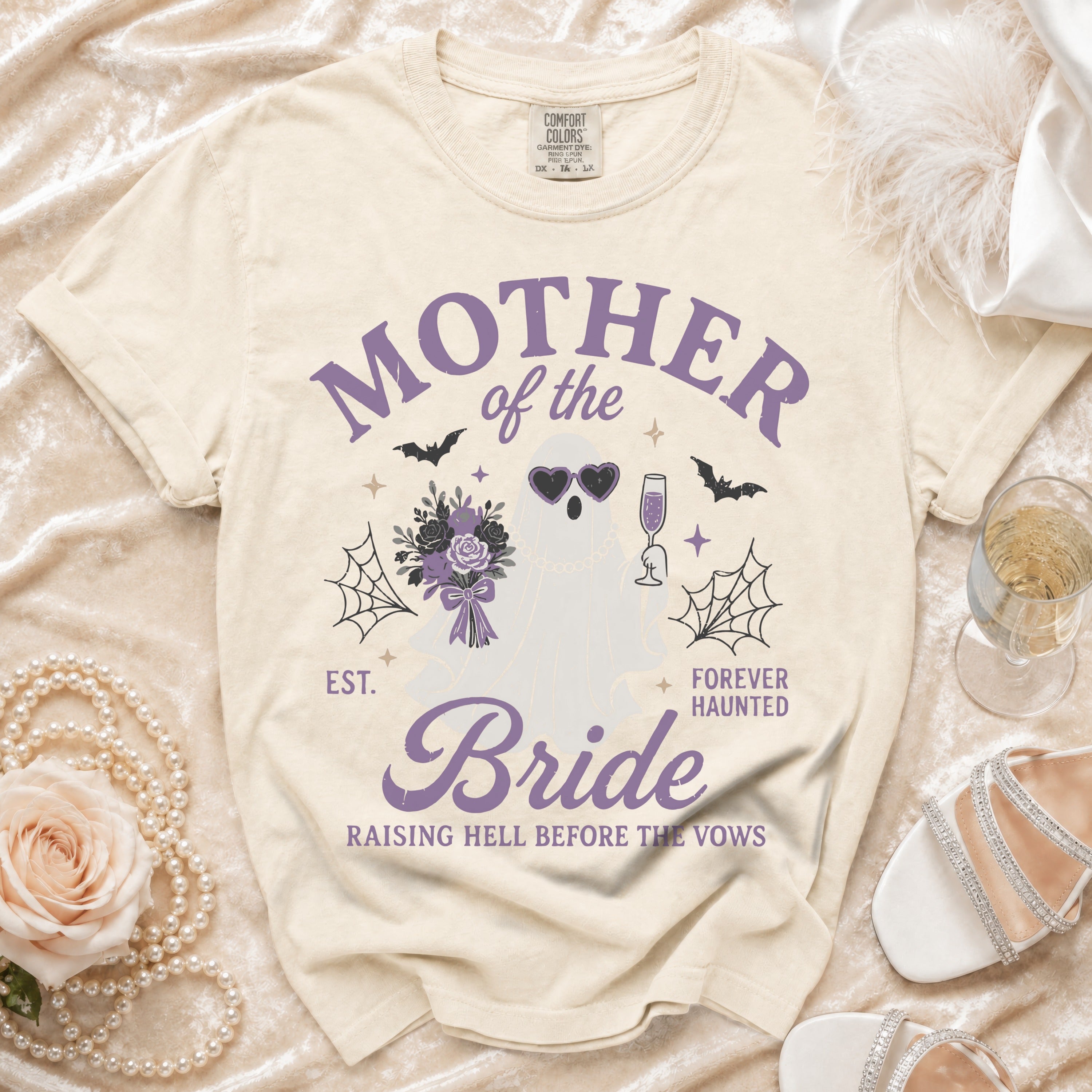 Cream t-shirt with purple text and ghost graphic reading "Mother of the Bride Forever Haunted".