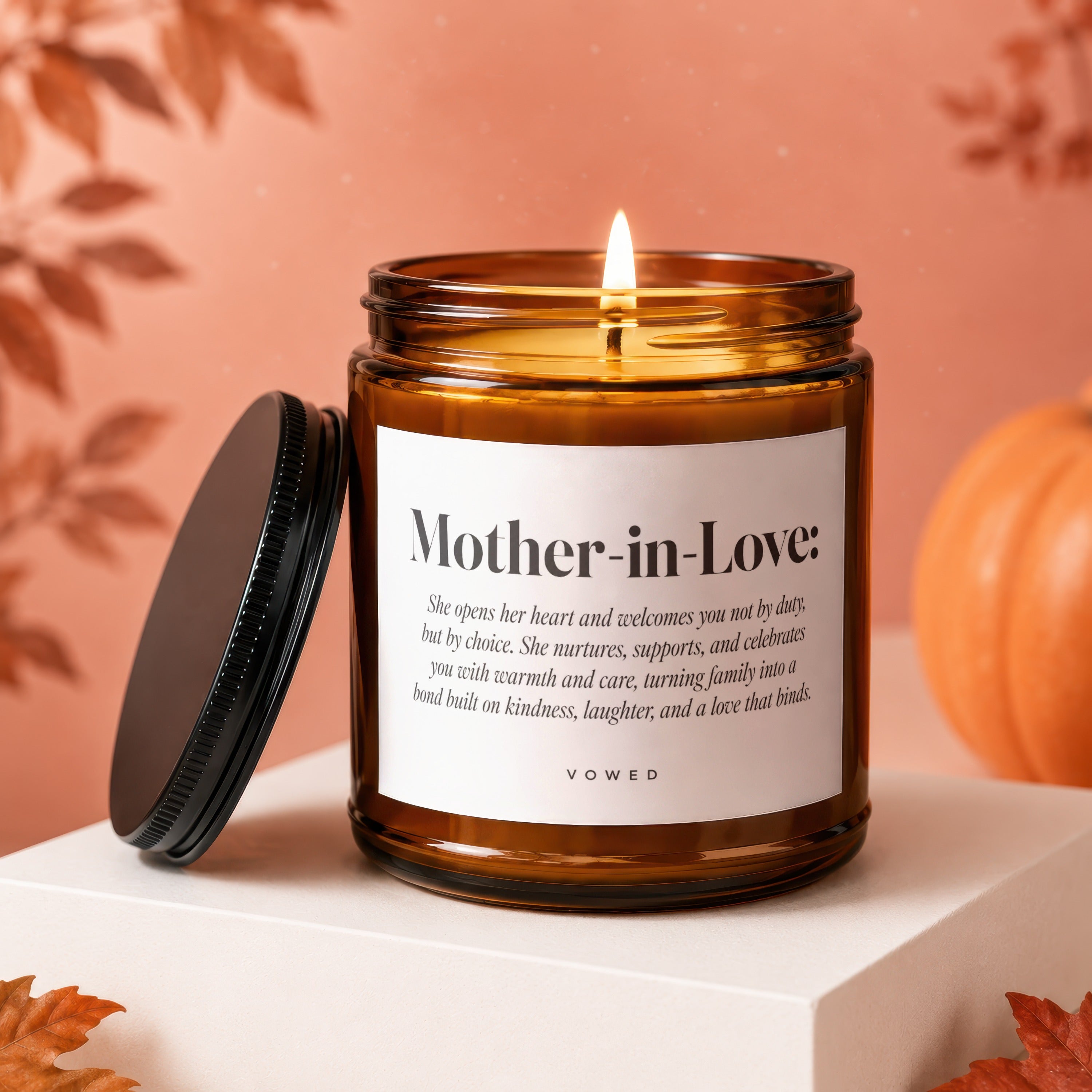 Amber candle with "Mother-in-Love" text and poem, lid off, pumpkin and leaves.