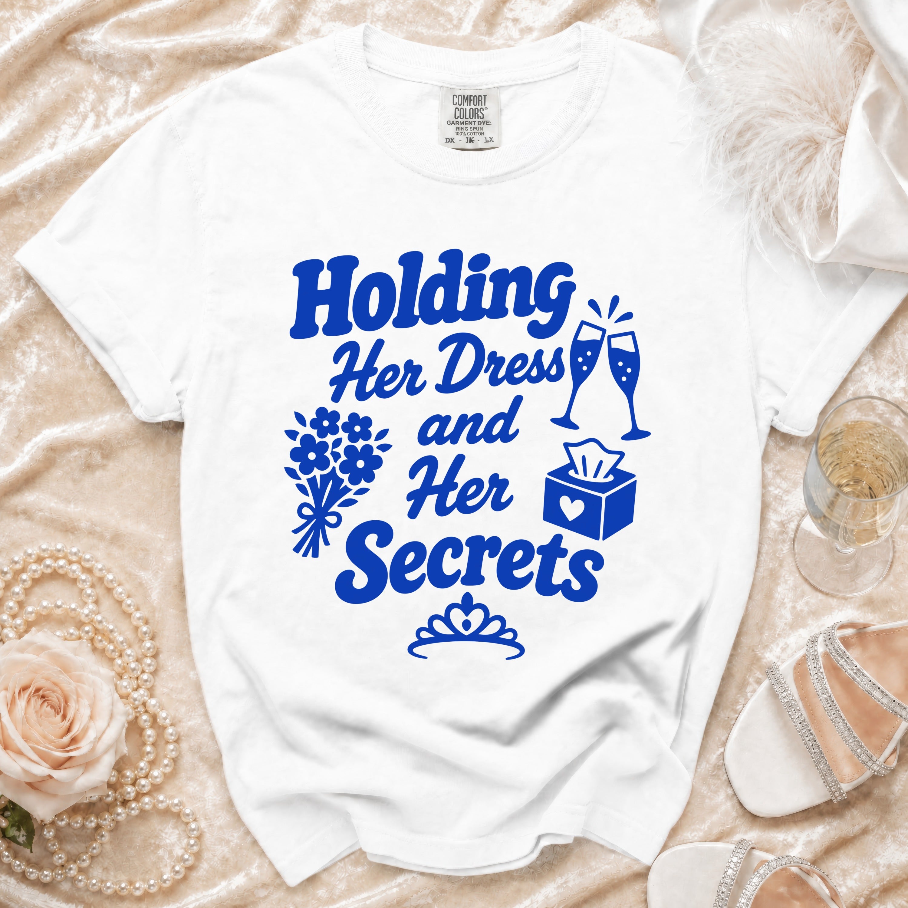 White t-shirt with blue text "Holding Her Dress and Her Secrets" and graphics.