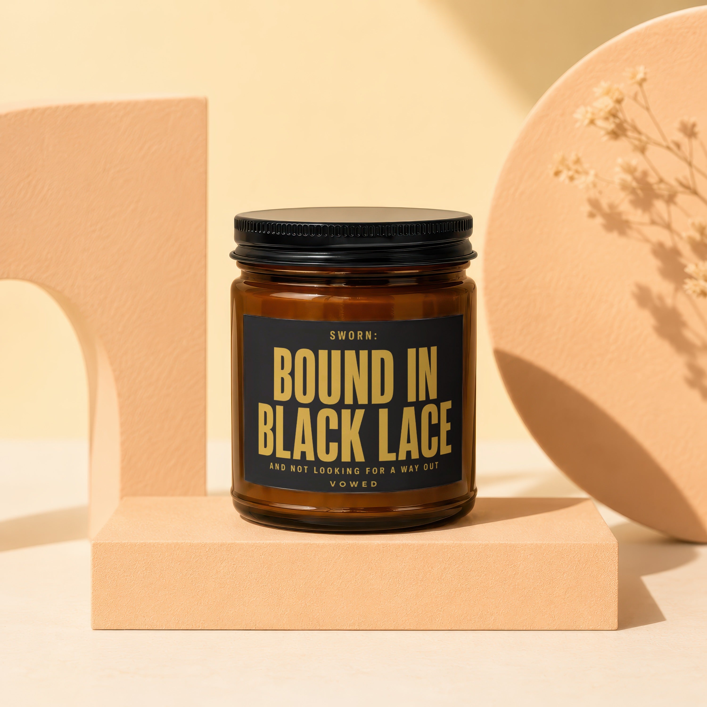 Amber candle in a glass jar with a black lid and "Bound in Black Lace" label.