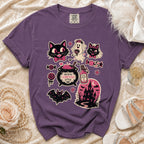 Purple t-shirt with Halloween-themed graphics including cats, a ghost bride, bat, cauldron, and haunted house.