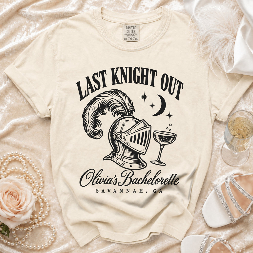 Cream t-shirt featuring a black graphic with a plumed knight helmet, champagne glass, and text reading LAST KNIGHT OUT OLIVIA'S BACHELORETTE SAVANNAH GA.