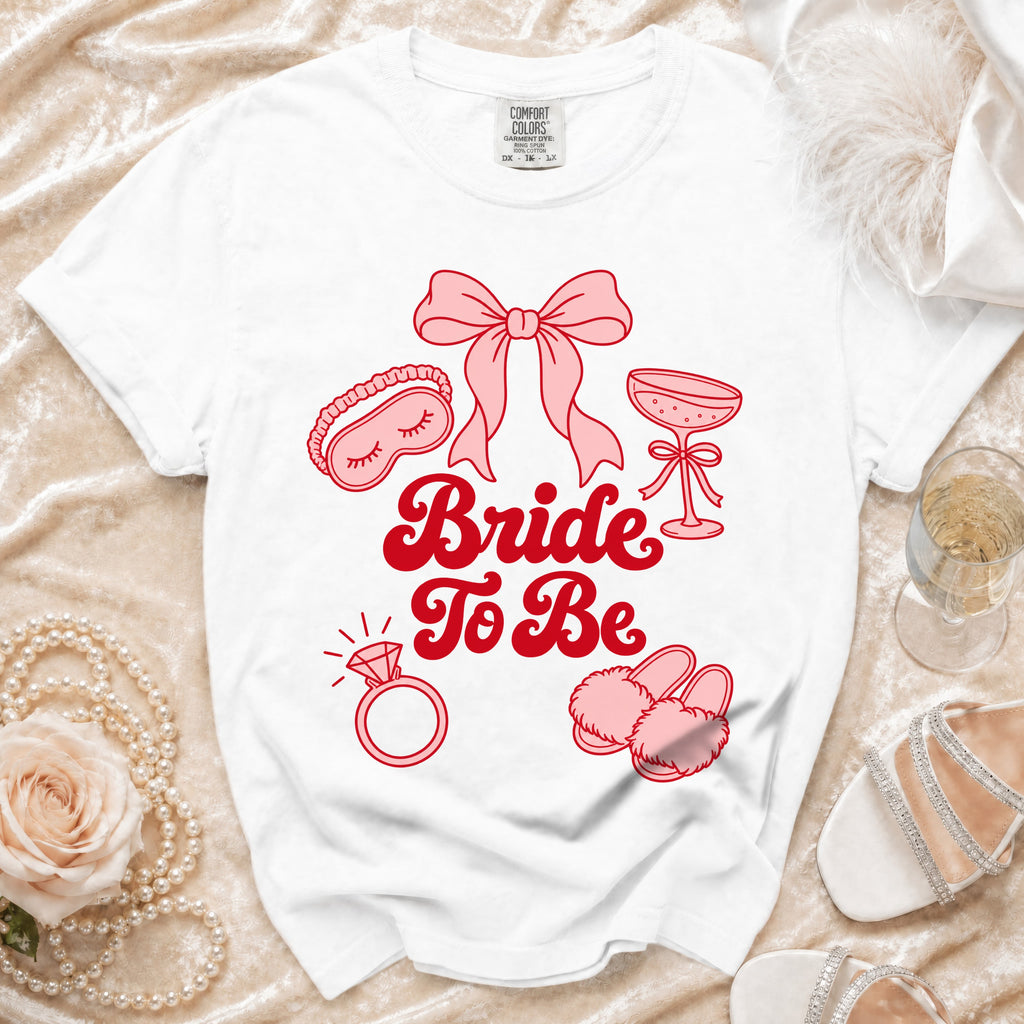 White t-shirt with pink "Bride To Be" text and wedding icons.