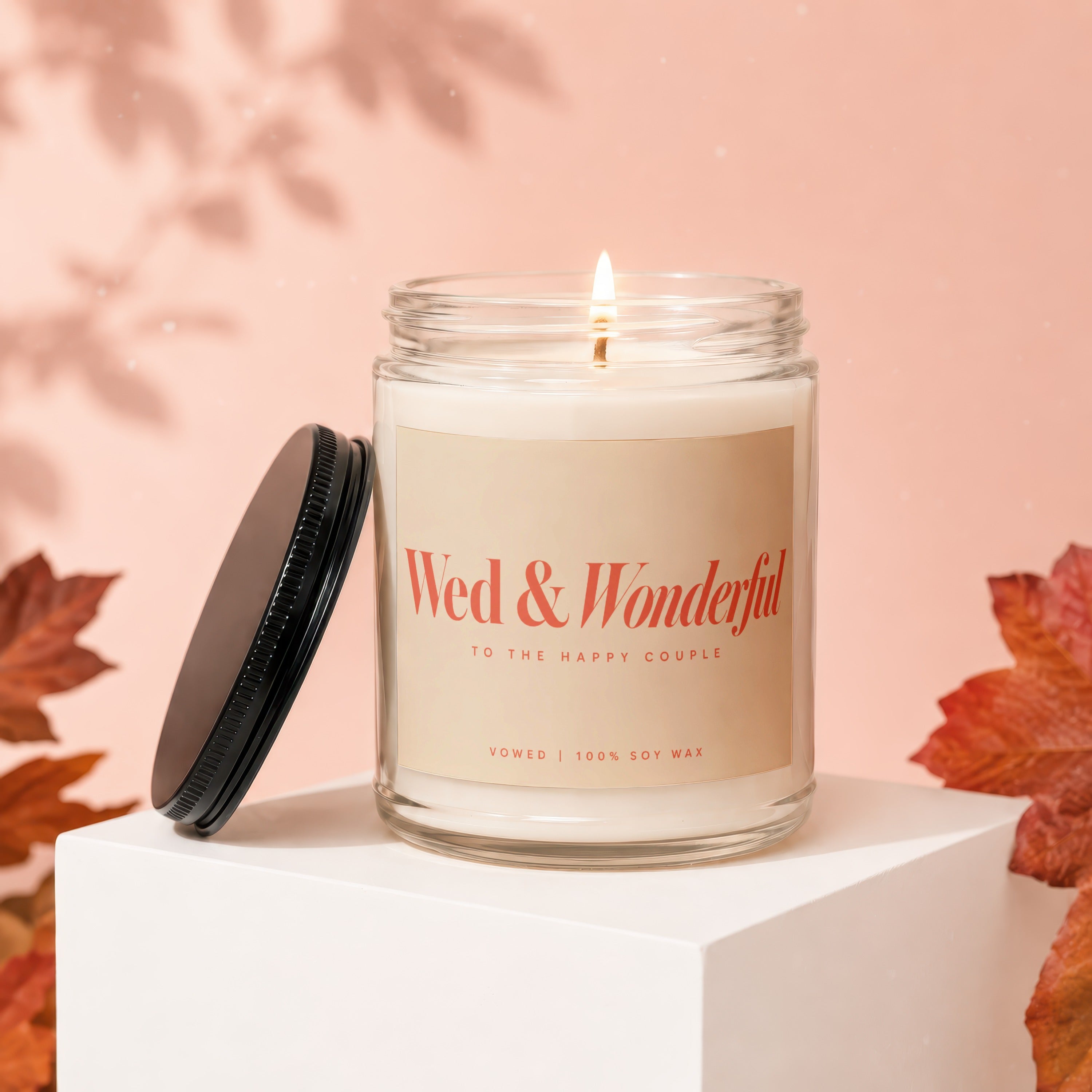 Lit glass candle with "Wed & Wonderful" label, lid off.