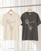 Ivory bride shirt printed in Pepper next to a Pepper crew shirt printed in ivory, Coastal Cowgirl tees