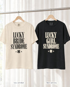 Ivory bride shirt printed in Black next to a Black crew shirt printed in ivory, Lucky Bride & Lucky Girl Syndrome tees