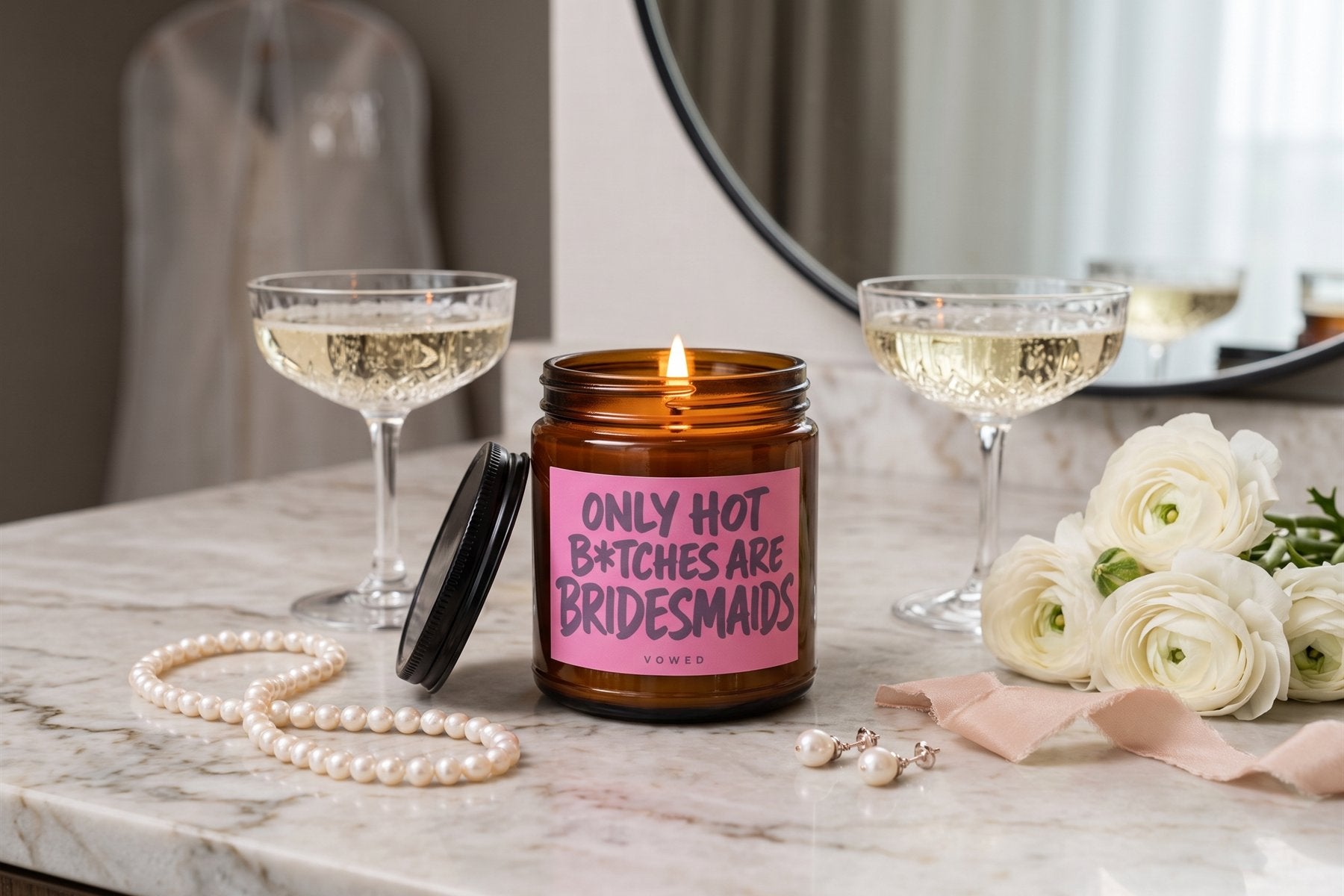 Lit Only Hot B*tches Are Bridesmaids candle on a hotel vanity with champagne, pearls and ranunculus